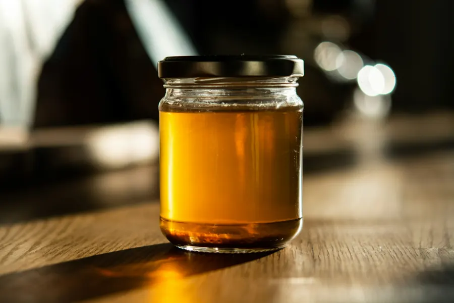Pot de miel de thym, ambré, sur une table en bois