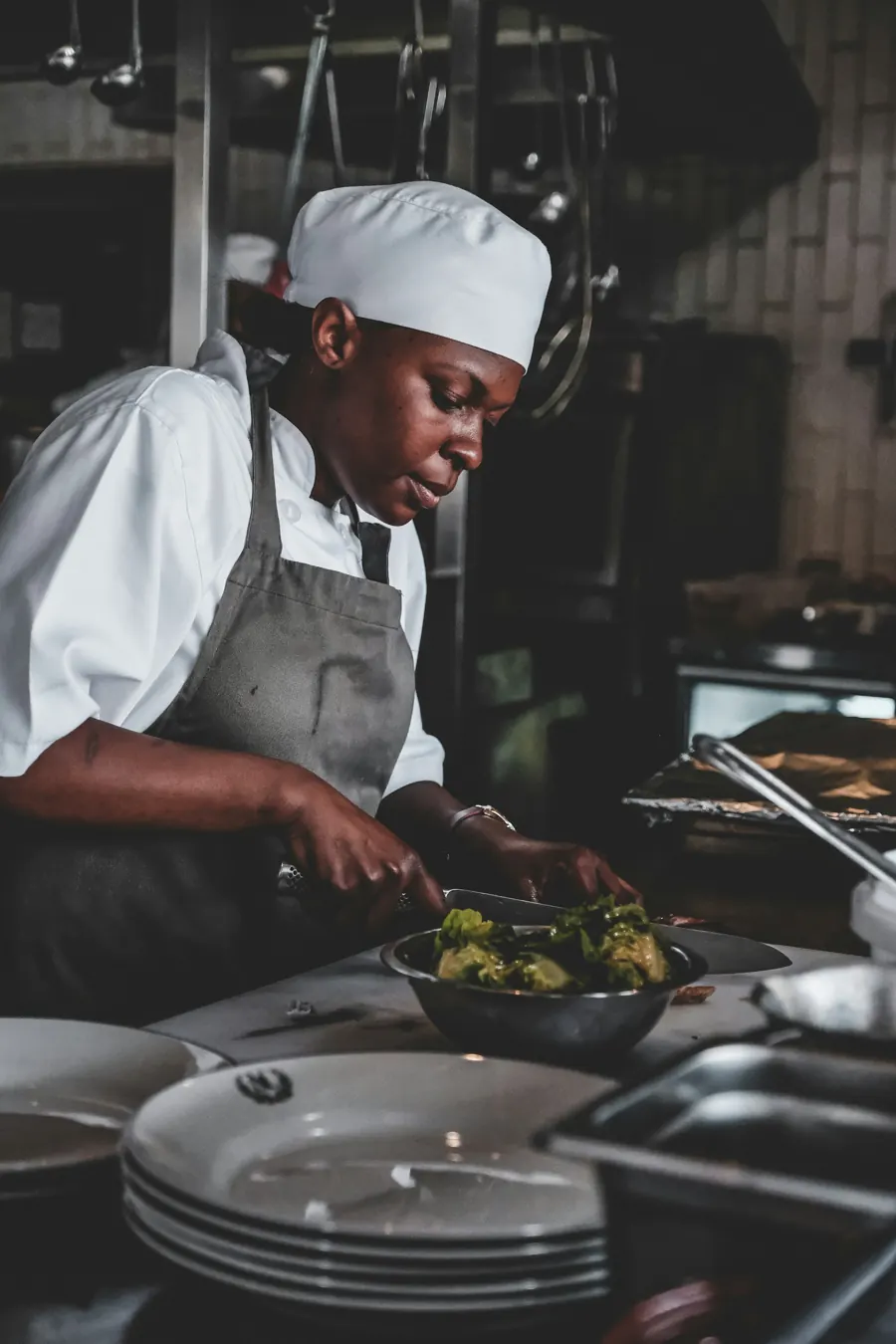 Camille Ferraud en cuisine, toque blanche, au-dessus d’une poêle